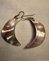 Both crescent shell earrings lying flat showing iridescence and hooks