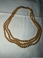Full view of four-strand gold faux pearl necklace