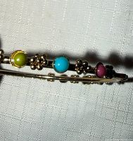 Side view showing cabochons and floral motifs on gold-tone bangle