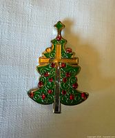Front view of gold-tone Christmas tree brooch with cross and red/green enamel