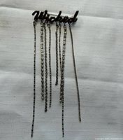 Front view of brooch showing script word and dangling chains