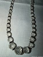 Full view of necklace laid flat showing graduated clear beads and black spacers