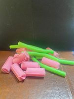 Pile of pink foam rollers with clips and green flexi rods