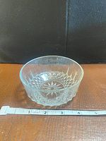 Side view of clear pressed glass bowl showing faceted sides and tape measure indicating size