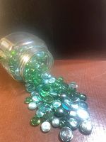 Jar of green and aqua glass pebbles spilled to show quantity, colors and condition