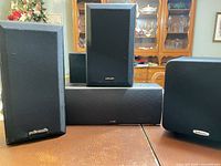 Front view of four Polk Audio speakers: two bookshelf, one center, one subwoofer