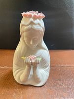 Front view of white porcelain female figurine holding pink rose