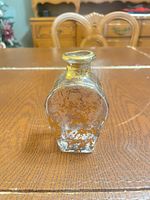 Front view of clear glass bottle showing gold paint loss