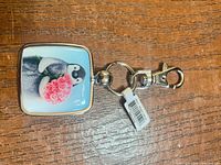 Front view of the keychain showing penguin with pink roses and metal frame