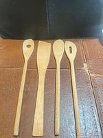 Four wooden utensils laid side by side on table