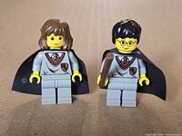 Front view of Hermione and Harry minifigures showing uniforms, faces, cape fronts and wand