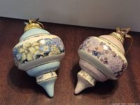 Two floral porcelain ornaments, blue and pink, on table