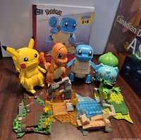 Group shot of four assembled Pokémon figures, terrain bases and Squirtle manual
