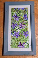 Front view of framed artwork showing floral and insect design