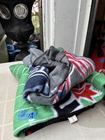 Folded blankets showing grey, red, blue stripe and green maple leaf design
