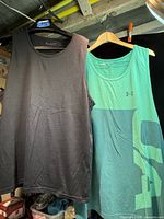 Front view of two Under Armour cotton tank tops, black and teal graphic