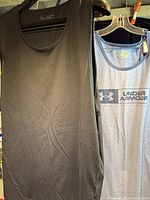 Black tank top and partial view of blue graphic tank top on hangers