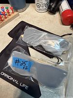 Two plastic-wrapped sunglasses, pouch, cloth