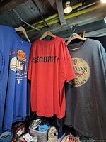 Three T-shirts hanging: blue Curious George, red Security, grey Guinness