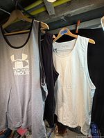 Three tank tops on hangers: grey with logo, dark grey, white