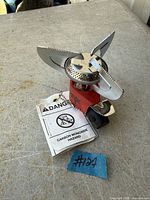 Stove front view with pot supports unfolded, warning tag visible