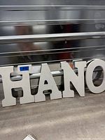 Front view of four white wooden letters H A N O