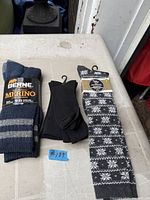 Three pairs of new socks on table: Berne merino wool, black crew, grey snowflake knee-high