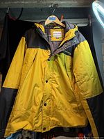 Front view of yellow and black hooded winter jacket hanging on hanger