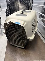 Front angled view of plastic Petmate Pet Taxi carrier showing wire door and ventilation holes