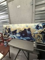 Full view of vinyl wall art on chair, showing abstract blue, white, gold design