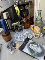 Group shot of all curios including bottles, flasks, phone, owl planter, massager and trivet