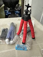 Assembled red flexible tripod with phone clamp, sealed blue and red tripods in plastic