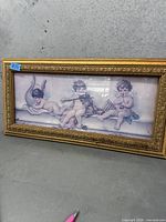 Front view of framed cherub print in gilt wood frame