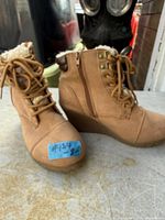 Side view of both tan wedge winter boots showing uppers, laces, faux fur lining