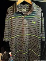 Front view of striped Under Armour polo on hanger