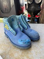 Pair of blue Timberland kids boots viewed from front/side