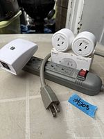 Lot overview showing power strip, two Gosund smart plugs on box, WiOn smart plug