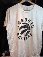 Front view of white Raptors T-shirt showing logo and size tag