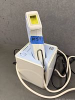 Front angled view showing Silk'n laser hair remover seated in charging base with cord