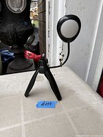 Full view of black mini tripod with screw mount and attached circular LED light on gooseneck arm