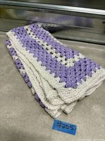 Folded vintage hand-knitted purple and cream blanket