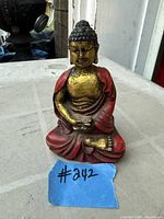 Front view of red and gold seated Buddha figurine with #242 tag