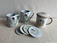 Front view of two Dunoon mugs, four matching coasters and one Korean lidded mug