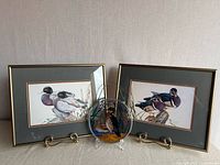 Group view of two framed prints and stained glass panel