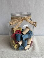 Jar filled with multi-coloured wooden spools