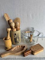 Group shot of utensil crock, measuring cup, wooden utensils, mooncake mold, tamper and mortar/pestle