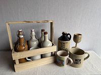 full lot showing bottles in caddy, jug, mugs, wood goblet
