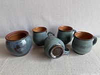 Front view of four mugs and bowl, showing exterior glaze and shapes