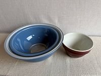 Three bowls: two blue Pyrex nested, one maroon Hall