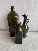 Front view of three olive green glass bottles with corks